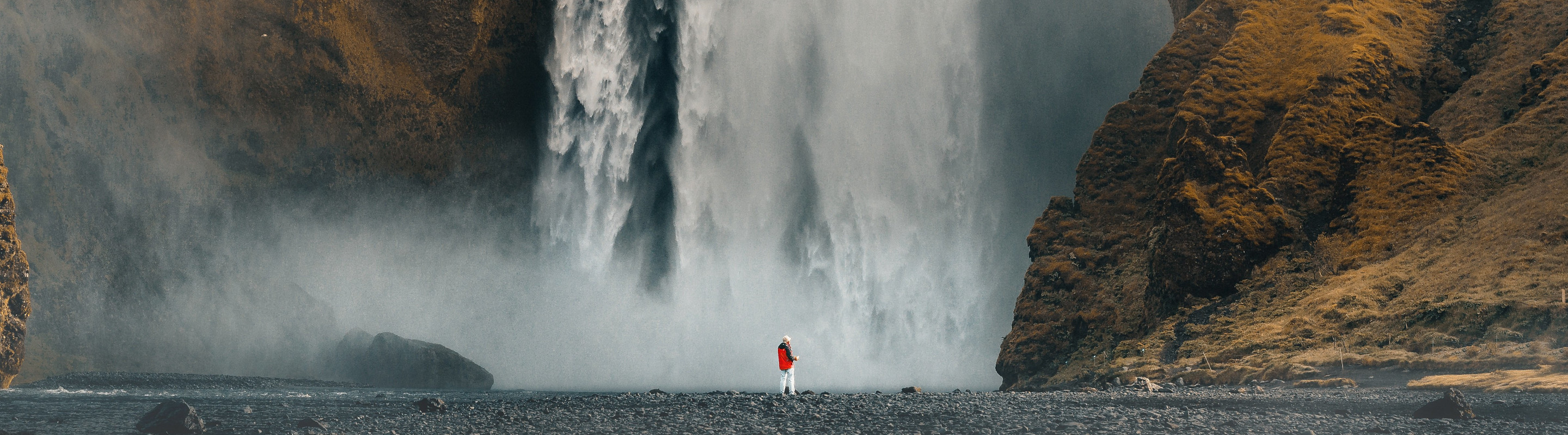 Person standing in front of a massive waterfall in Iceland