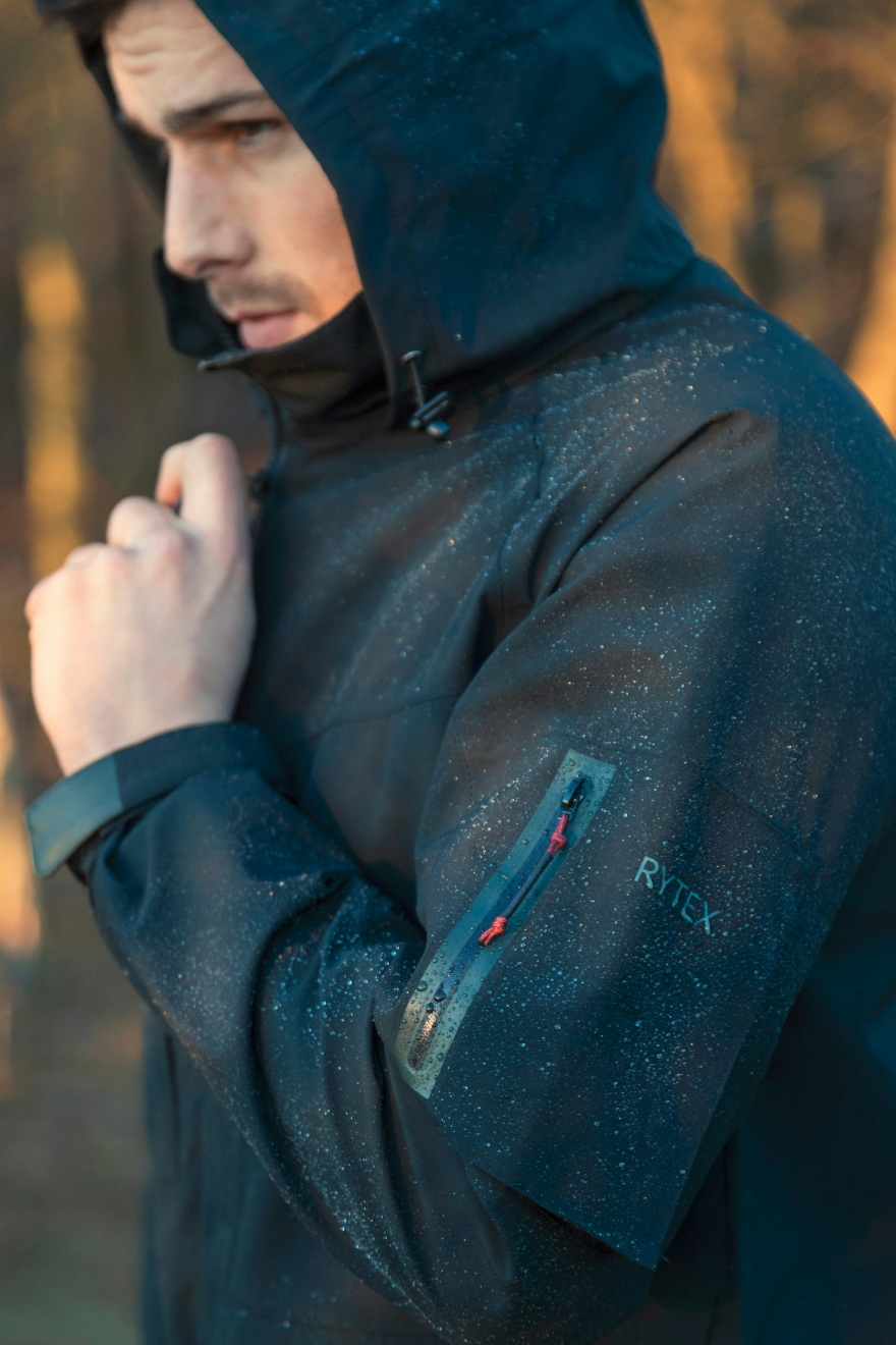 Male model standing wearing a blue waterproof jaket